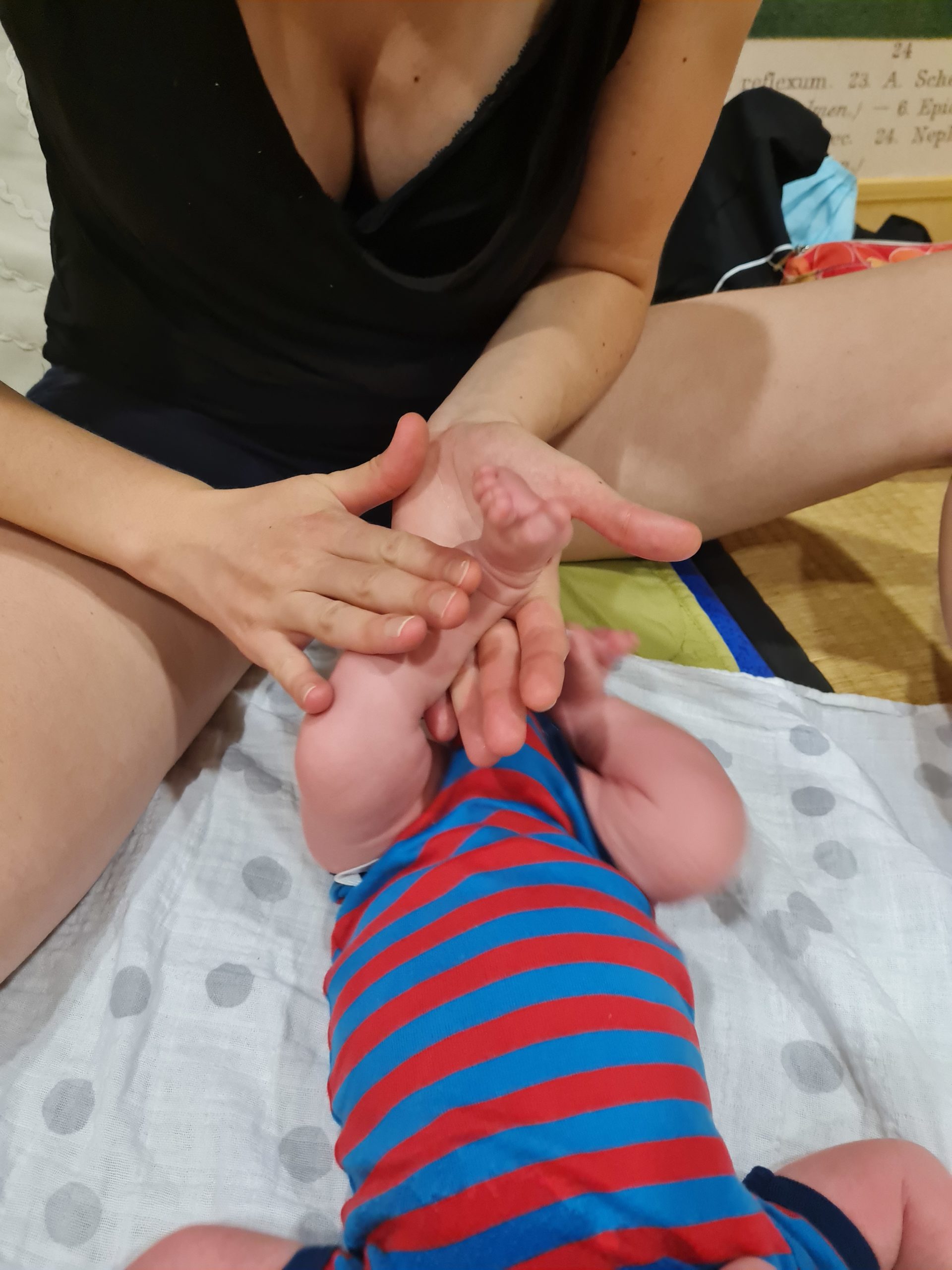Jeune maman massant la jambe de son bébé lors d'un atelier avec une instructrice en massage bébé