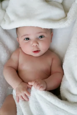 Bébé emmitouflé dans une couverture pour ne pas avoir froid durant la séance de massage bébé.