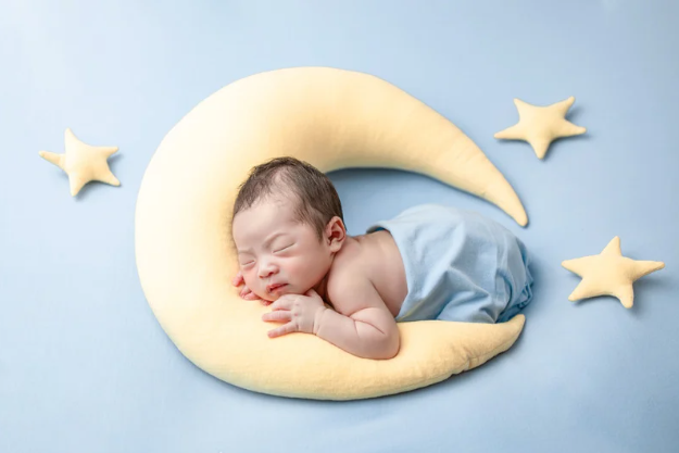 Bébé détendu dans un univers du rêve, avec des coussins, des étoiles et une lune.