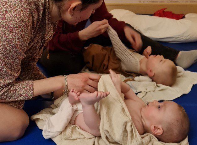 Deux mamans massant leur bébé lors d'un atelier massage bébé.