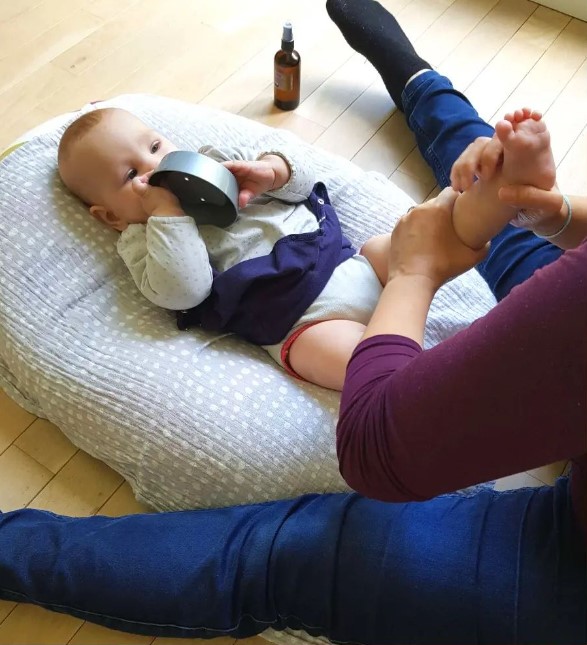 Jeune maman en train de masser son bébé lors d'une séance de massage bébé.